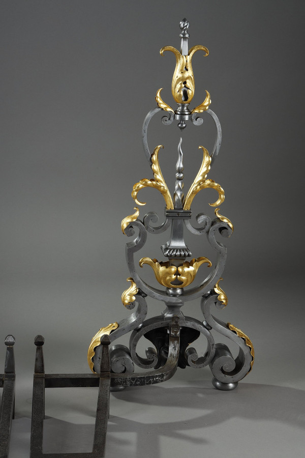 Paire de landiers en fer forgé à décor feuillagé, masque et volutes