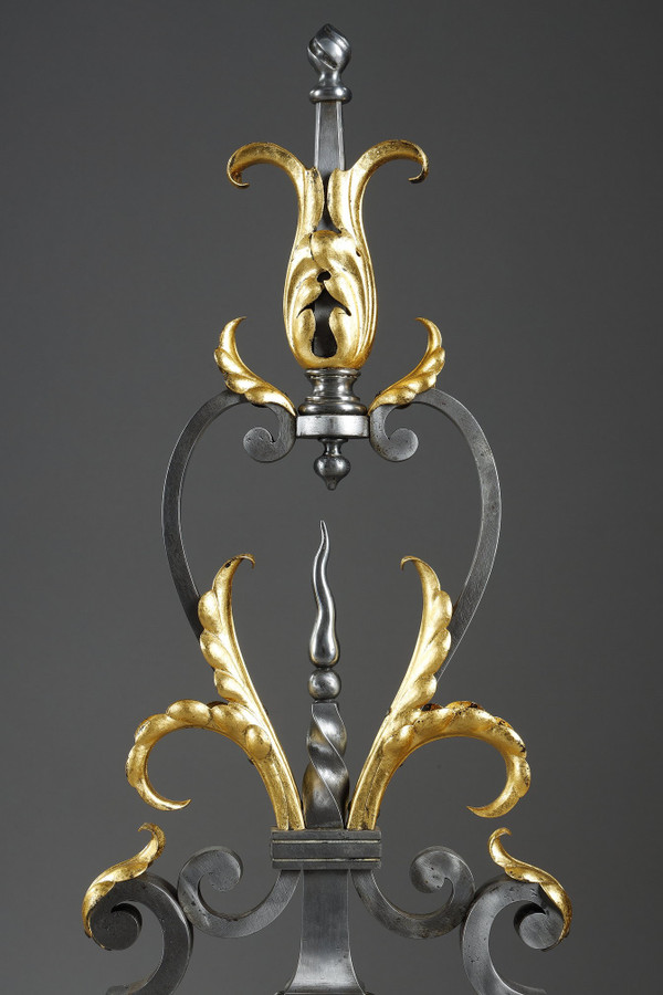 Paire de landiers en fer forgé à décor feuillagé, masque et volutes