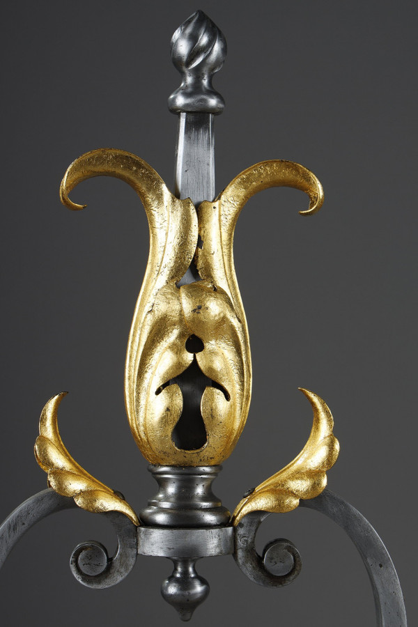 Paire de landiers en fer forgé à décor feuillagé, masque et volutes