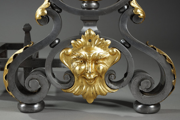 Paire de landiers en fer forgé à décor feuillagé, masque et volutes