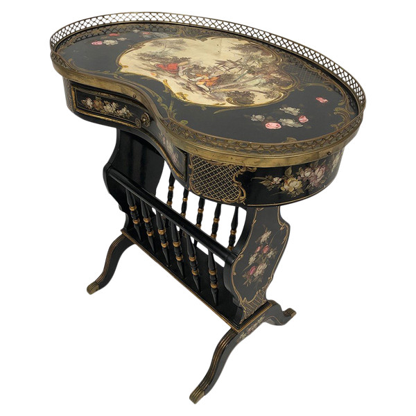 Petite table de forme rognon en bois laqué noir et riches décors peints, formant porte-revues.
