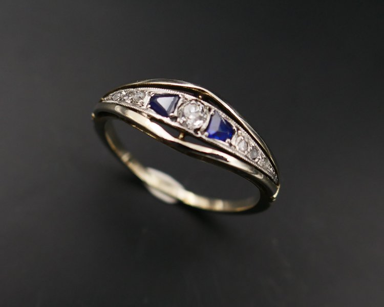 Anello giarrettiera con diamanti e zaffiri calibrati, oro e platino.
